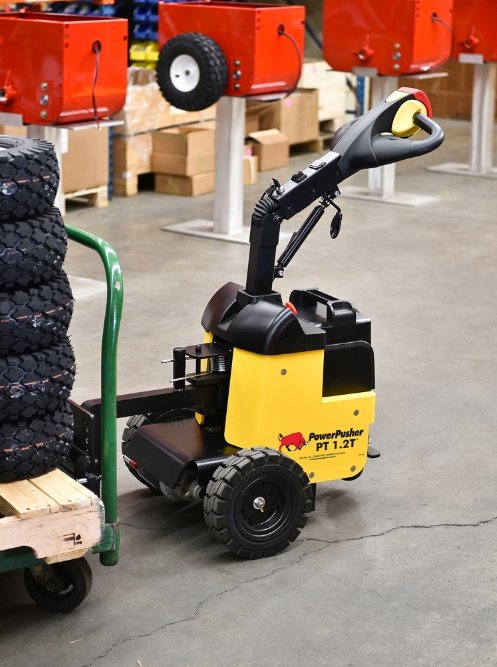 PT 1.2T™ electric tug navigating warehouse floor with stacked boxes