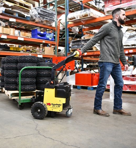 PT 1.2T battery-powered tug maneuvering heavy load in warehouse
