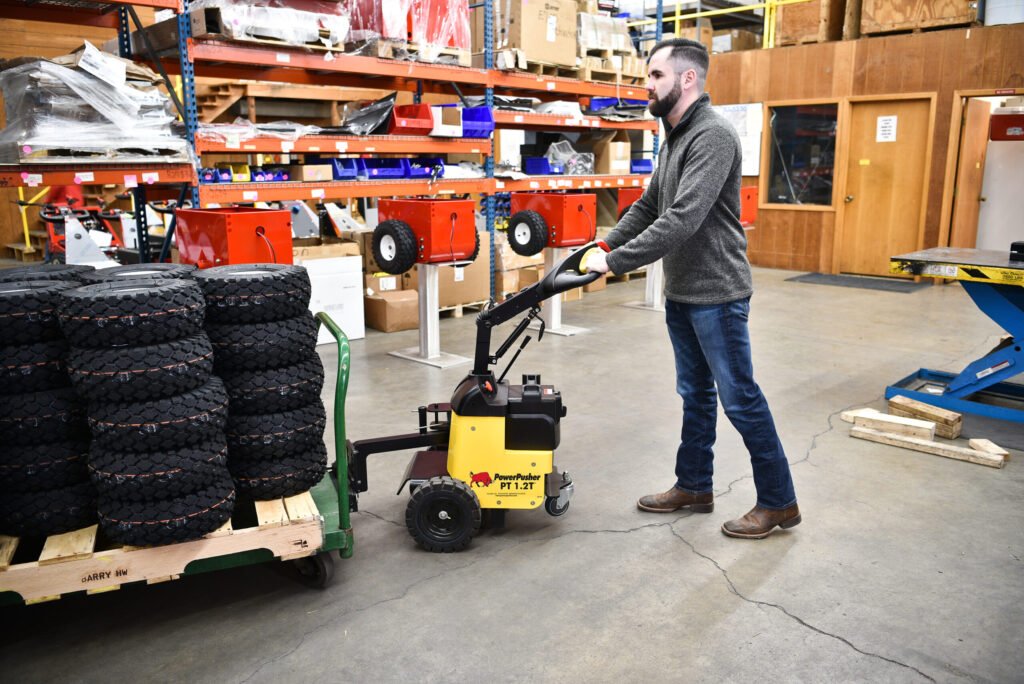 the PT 1.2T™ battery-powered tug is adeptly transporting multiple stacked boxes within a warehouse