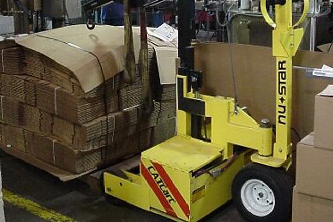 Warehouse worker lifting a cardboard box onto a pallet
