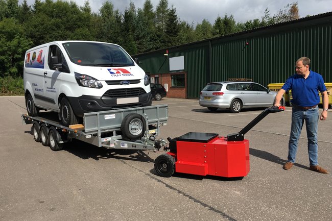 Heavy-Duty Trailer Mover™ towing a passenger car on a trailer in an industrial setting